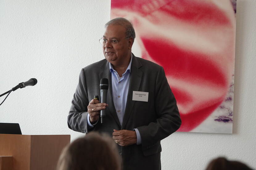 NCDR Rabin Baldewsingh spreekt een zaal toe met een microfoon in zijn hand.