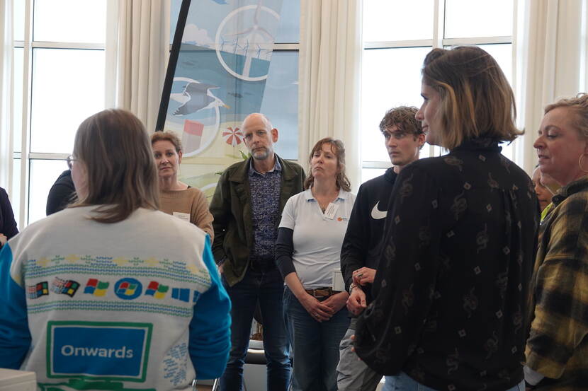 Een groep deelnemers van de townhall-sessie staat in een kring.